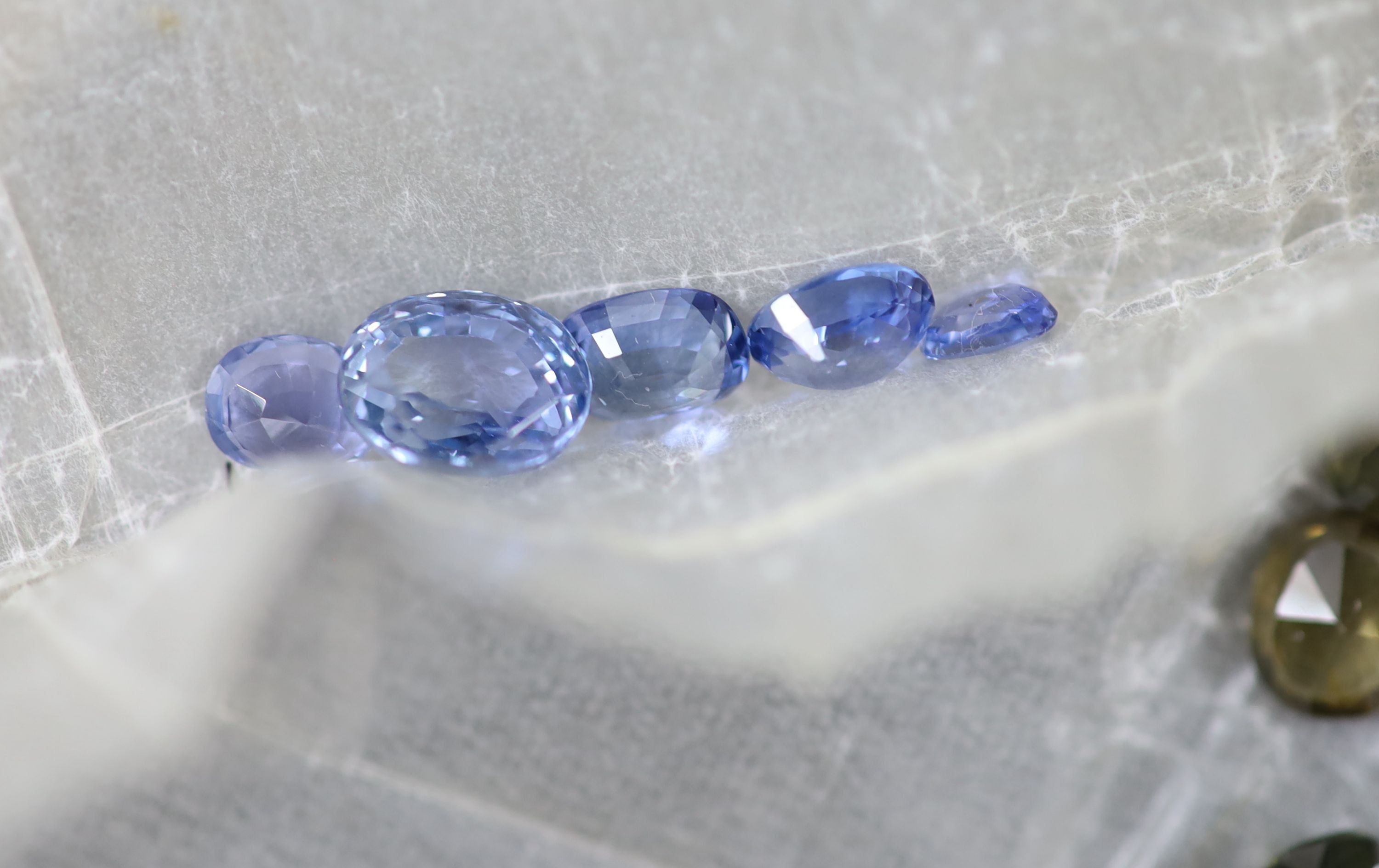 A quantity of assorted loose cut gemstones including sapphires, aquamarine, citrine and tourmalines.